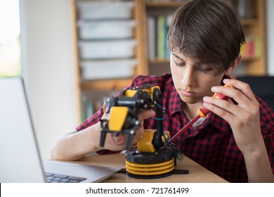 Teenage Boy Building Robotic Arm At School