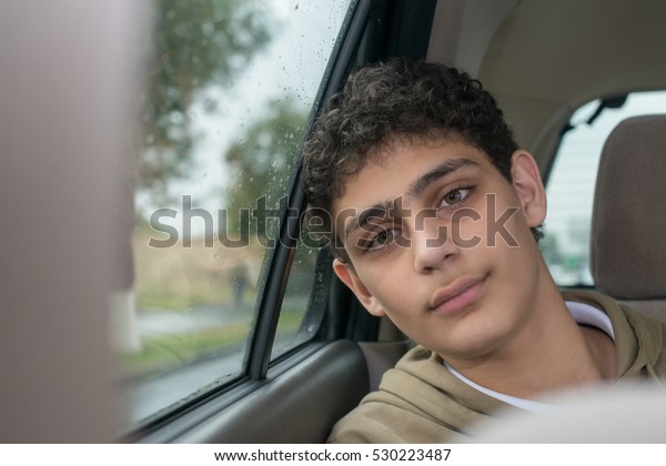 Teenage boy in a\
car with a rainy autumn\
weather