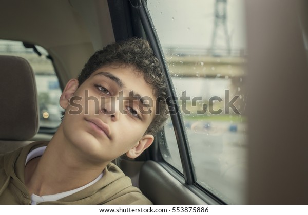 Teenage boy in a car\
with a rainy weather