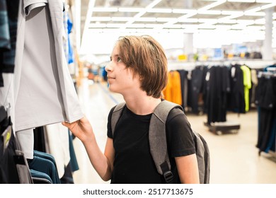 teenage boy chooses clothes for himself in a store - Powered by Shutterstock