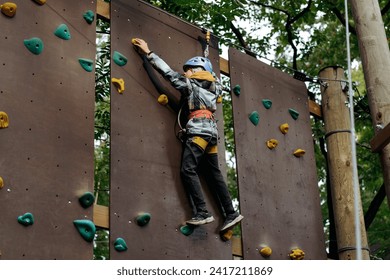 teenage boy climbing up the wall in outdoor adventure park passing obstacle course. high rope park - Powered by Shutterstock