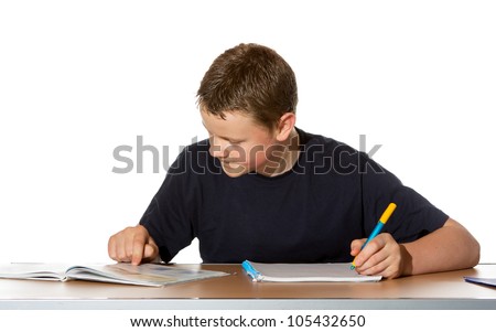 Teenage boy concentrating on his studies as he makes notes in a book from the information he is researching in his textbook