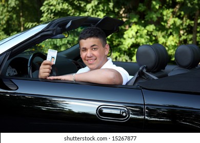 A Teenage Boy In A Convertible Holding His Drivers Permit.