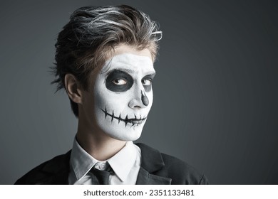 A teenage boy in a costume of skeleton posing at studio on a grey background. Halloween party for teenagers. Space for text. - Powered by Shutterstock