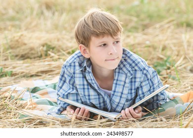 Teenage boy dreaming reading a book outdoor