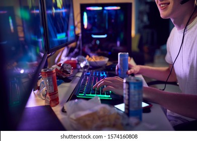 Teenage Boy Drinking Caffeine Energy Drink Gaming At Home Using Dual Computer Screens At Night