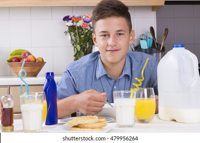 Teenage Boy Eating Cereal For Breakfast In Kitchen