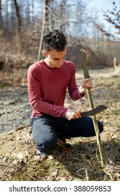 Teenage Boy In The Forest Making A Tool Using A Machete