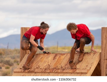 Teenage boy and girl climbing over an obstacle in a mud run obstacle course  - Powered by Shutterstock