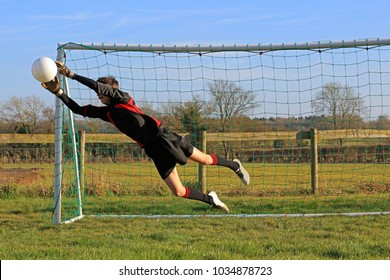 Teenage Boy Goalkeeper Saving A Football In A Game Of Soccer. - Powered by Shutterstock