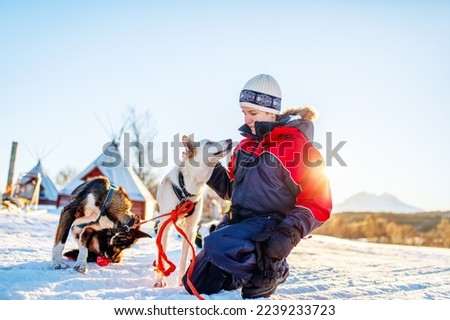 Teenage boy having a cuddle with husky sled dog in Northern Norway