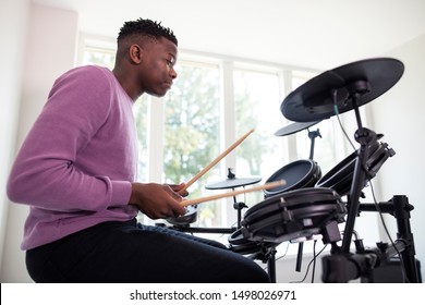 Teenage Boy Having Fun Playing Electronic Drum Kit At Home