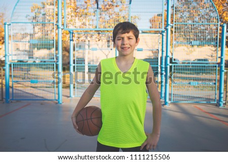 Teenage boy holding a basketball on a court