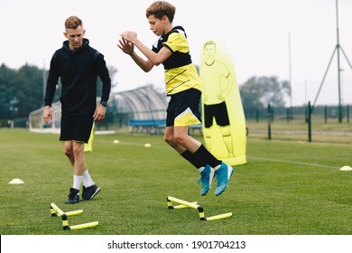 Teenage boy jumping over hurdles. Young soccer athlete practicing strength and agility skills. Boy of youth soccer team on training unit with personal trainer. Soccer coach coaches a young player - Powered by Shutterstock