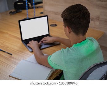 Teenage boy kid studying and doing homework on a desktop laptop computer, remote education and blank screen mock-up
