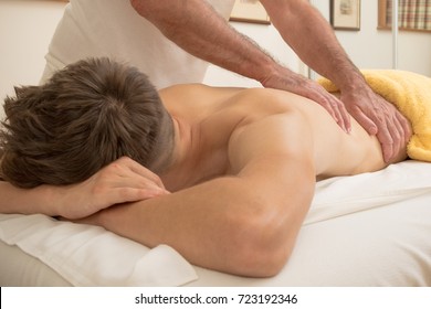 Teenage boy laying on a massage table, having a back massage