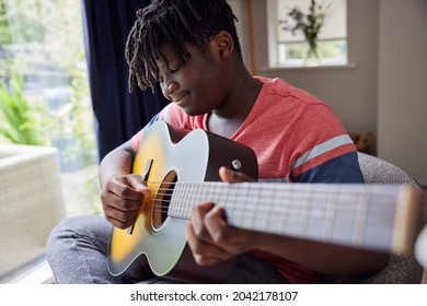 Teenage Boy Learning To Play Acosutic Guitar At Home - Powered by Shutterstock