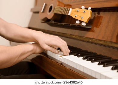 Teenage boy learning to play the piano and ukulele, his hands confidently pressing the keys, close up, music concept, focus on hands - Shutterstock ID 2364382645