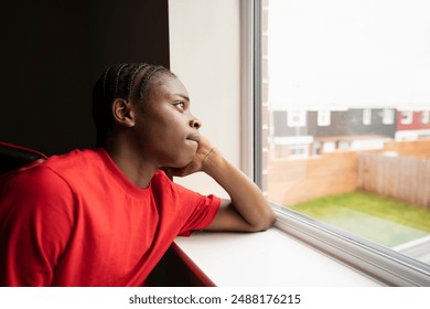 Teenage boy looking through window at home - Powered by Shutterstock