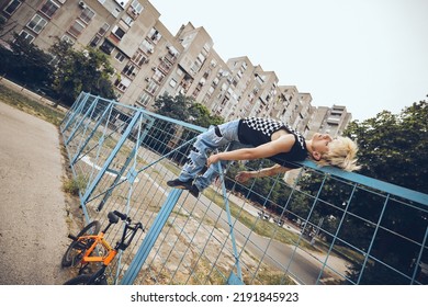 A teenage boy is lying on the fence outside and feeling misunderstood.