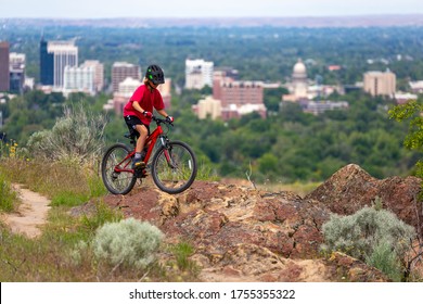 Teenage boy mountain biking on Table Rock above downtown Boise, Idaho