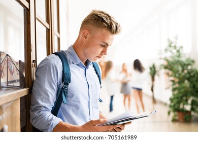 Teenage Boy With Notebooks In High School Hall During Break.