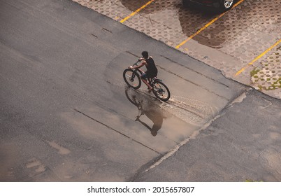 A teenage boy on a cycle riding over a puddle of rain water in the rainy season in India. Aerial photo of a person on the street. - Powered by Shutterstock