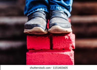 Teenage Boy On A Street In A Big City Next To A High-rise Building Alone. Concept Of A Teenager Parkour Life. Sneakers Close Up View