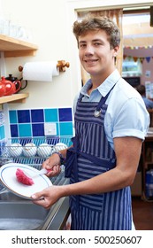 Teenage Boy With Part Time Job Washing Up In Coffee Shop