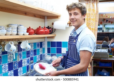 Teenage Boy With Part Time Job Washing Up In Coffee Shop