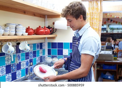 Teenage Boy With Part Time Job Washing Up In Coffee Shop