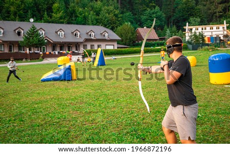 Teenage boy playing archery tag during summer