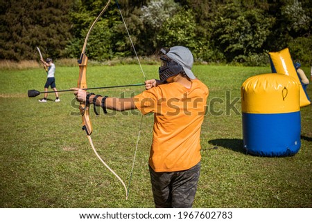 Teenage boy playing archery tag on a meadow