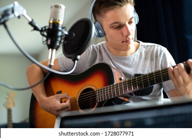 Teenage Boy Playing Guitar And Recording Music At Home