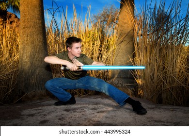 A teenage boy poses with a sci-fi light sword.
