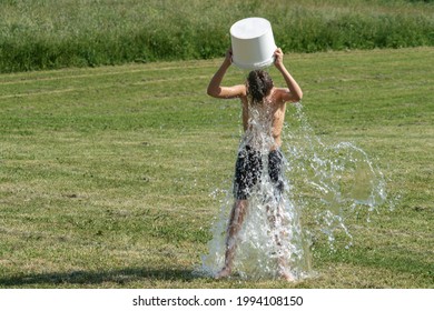 Teenage Boy Pouring Bucket Of Cold Water Over His Head Outdoors. Ice Water Challenge. Cold Water Therapy Benefits