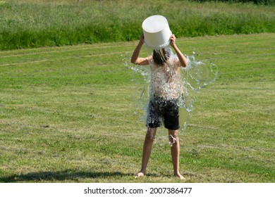 Teenage Boy Pouring Bucket Of Cold Water Over His Head Outdoors. Ice Water Challenge. Cold Water Therapy Benefits