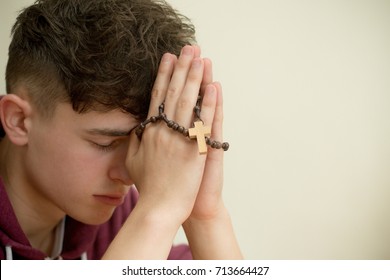 Teenage Boy Praying With A Rosary