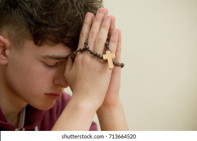 Teenage Boy Praying With A Rosary