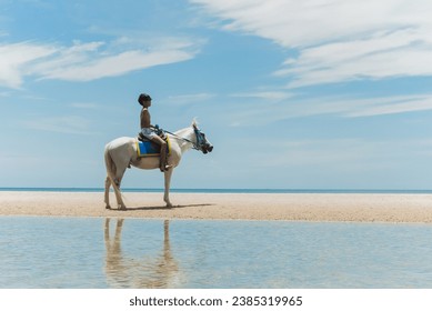 Teenage boy rides a horse on the beach. - Powered by Shutterstock