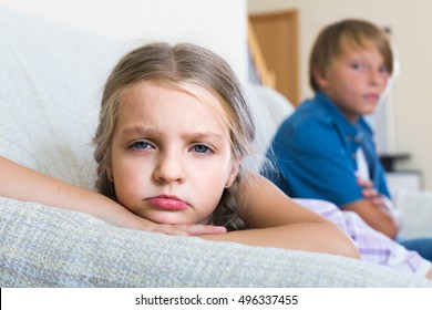 Teenage Boy And Sad Little American Girl Quarrelling At Home. Focus On Girl