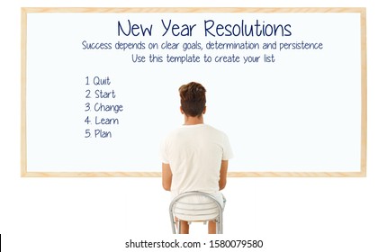 Teenage Boy Sitting With Back To Camera Looking At New Year Resolutions White Board 