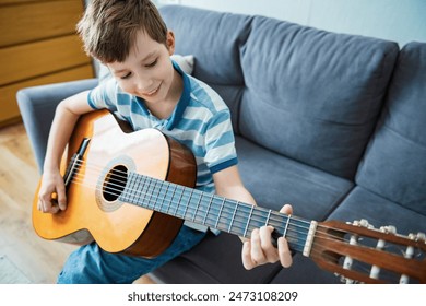 Teenage Boy Sitting On Sofa At Home Playing Guitar - Powered by Shutterstock