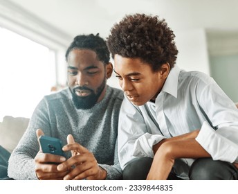 Teenage boy sitting at sofa with his father and using phone. Father and son bonding and having fun at home  - Powered by Shutterstock