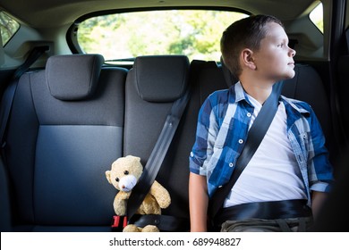 Teenage Boy Sitting With Teddy Bear In The Back Seat Of Car