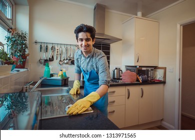 Teenage boy is smiling for the camera while cleaning a kitchen.  - Shutterstock ID 1313971565