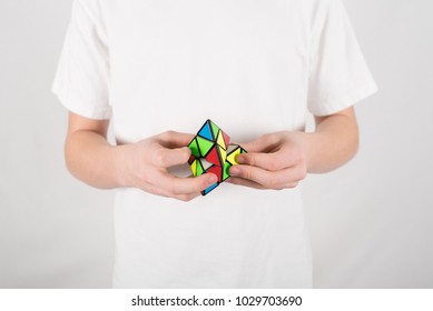 Teenage Boy Speed Solving 4-sided Pyraminx Pyramid Puzzle In White T-shirt Against White Background