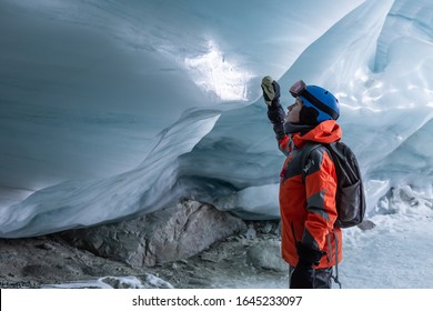 A teenage boy takes a close up look at a the ice wall of a glacial cave in the backcomb glacier while skiing. Whistler, BC,  Canada. - Shutterstock ID 1645233097