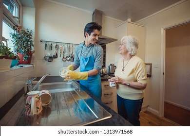 Teenage boy is talking to his grandmother while he washes the dishes in her kitchen. - Powered by Shutterstock