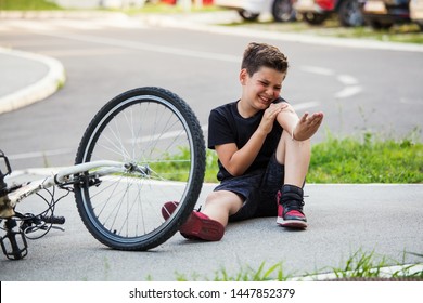 Teenage Boy There Is A Elbow Injury, As The Bike Falls While Riding. Kid Hurts His Arm After Falling Off His Bicycle. Child Is Learning To Ride A Bike